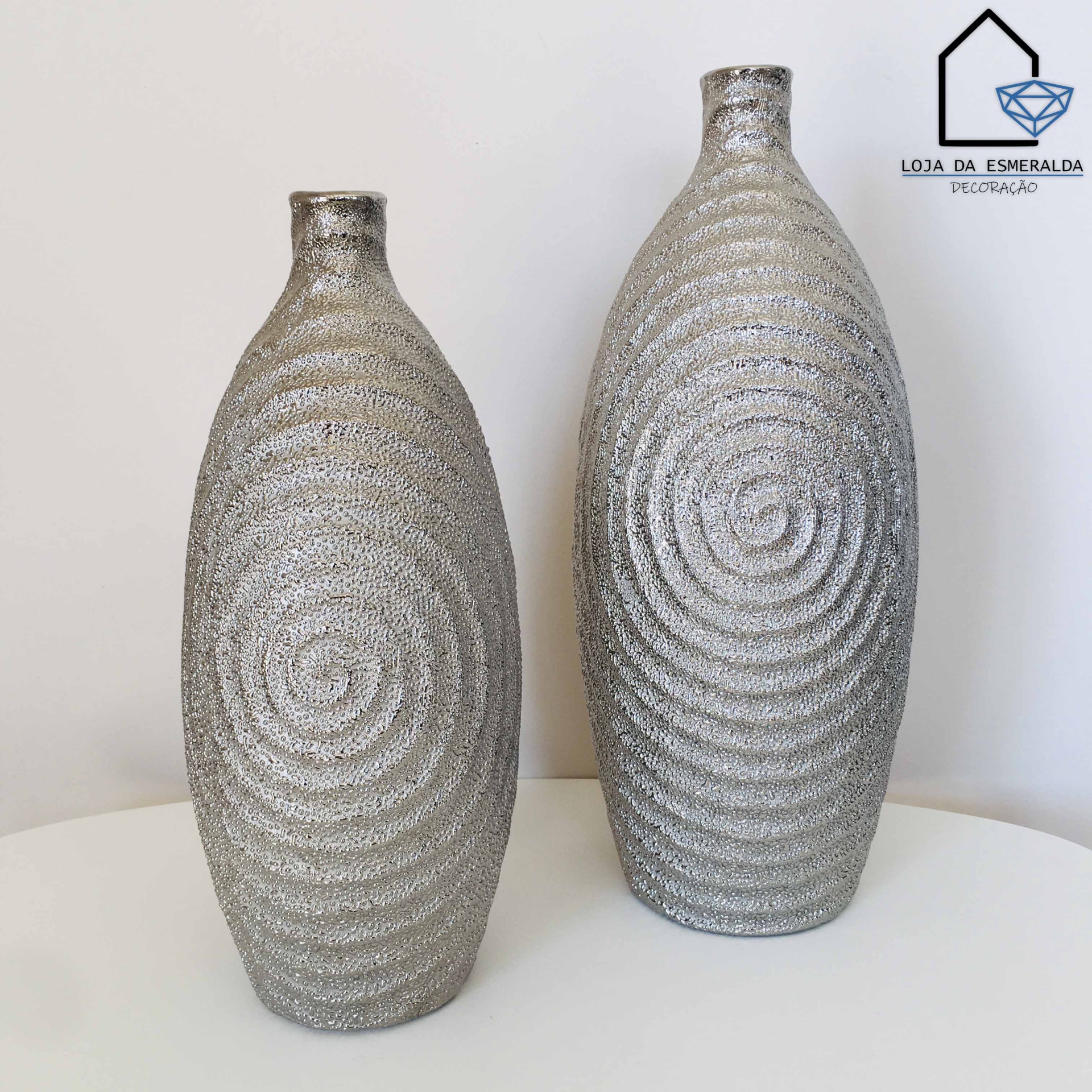 Dois vasos prateados com padrão espiral numa superfície branca
