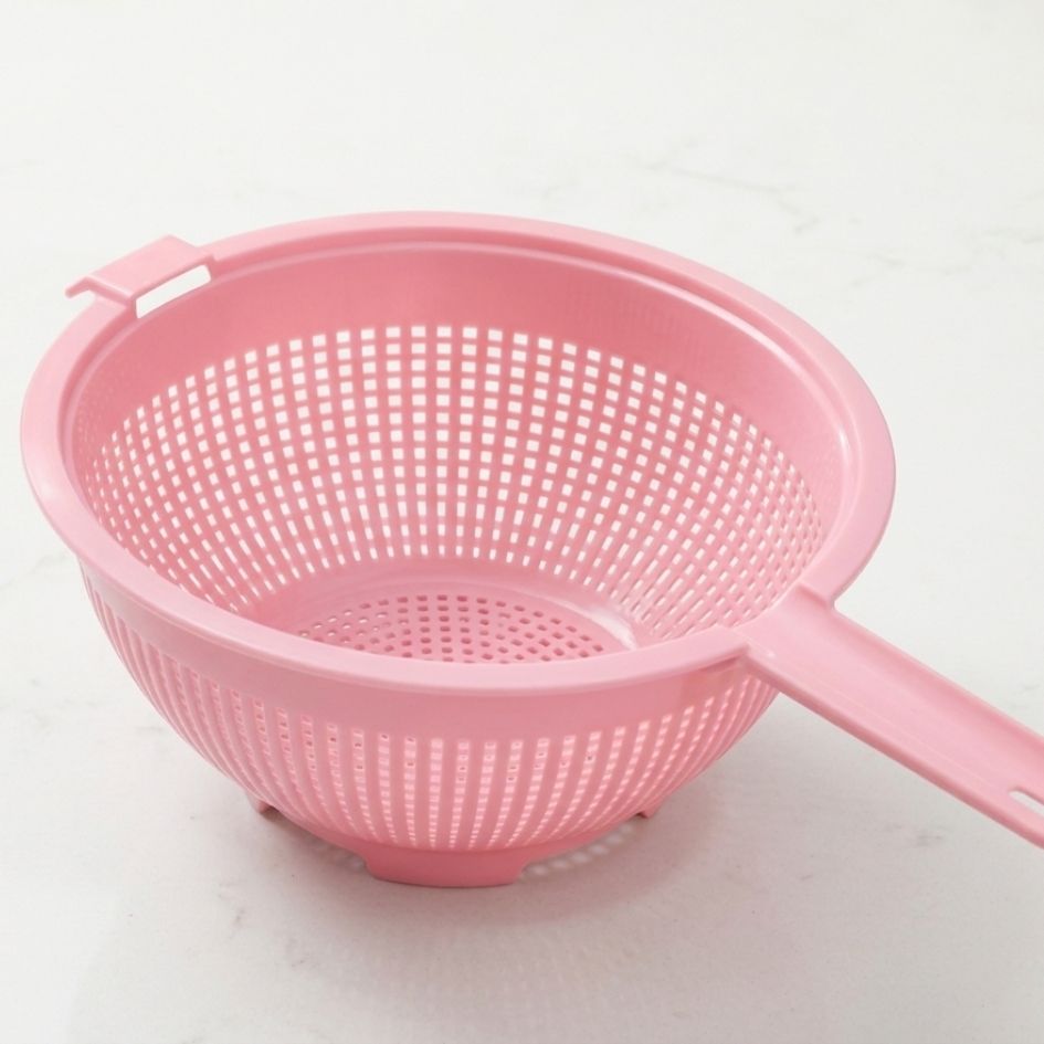 Escorredor de plástico rosa com alça e furos quadrados