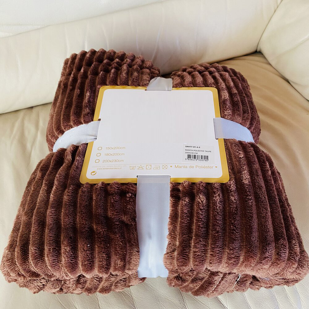 Manta castanha riscada em dobra sobre sofá claro