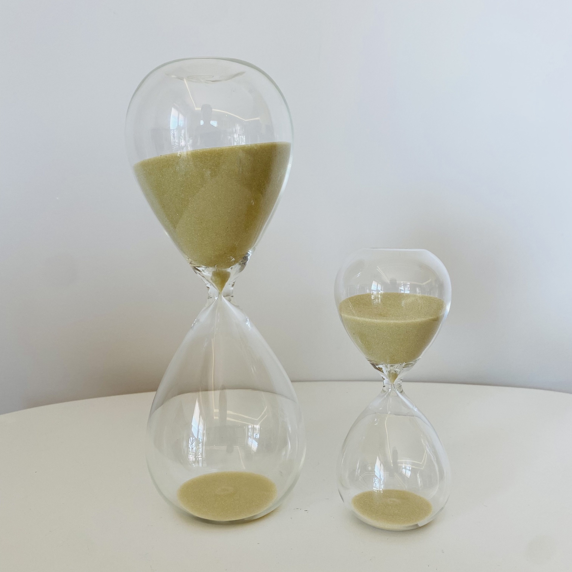 Ampulhetas de vidro transparentes com areia bege em fundo branco