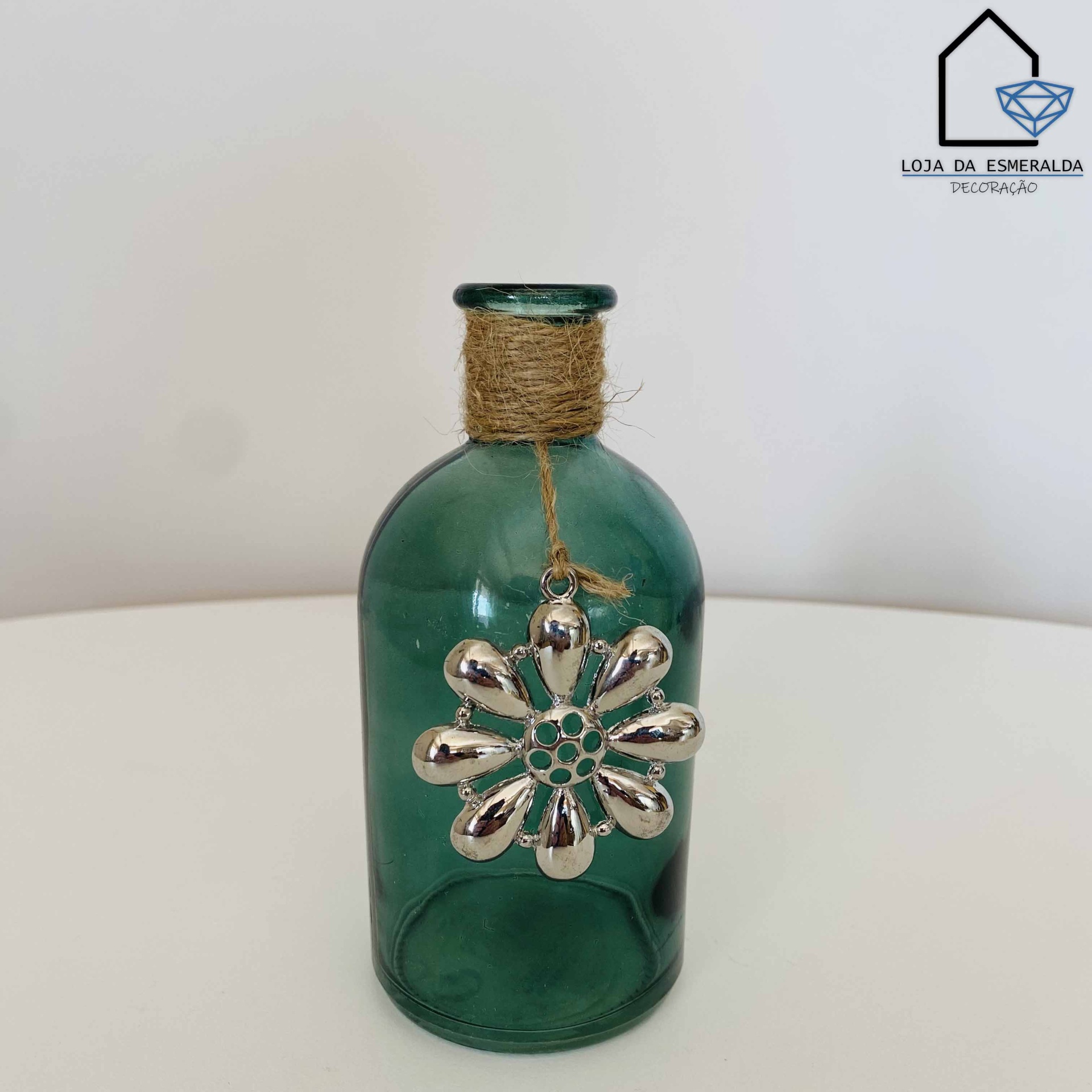 Garrafa de vidro verde com decoração metálica prateada em forma de flor