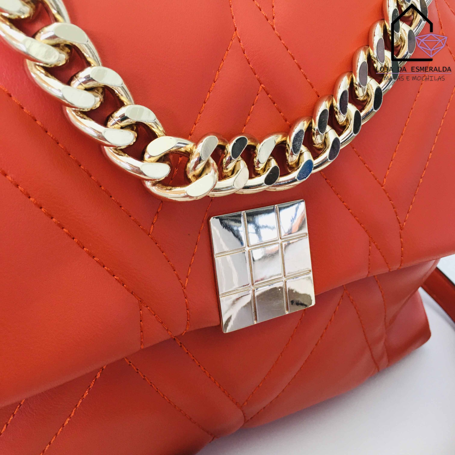 Mala laranja com costura geométrica, corrente dourada e fecho metálico prateado