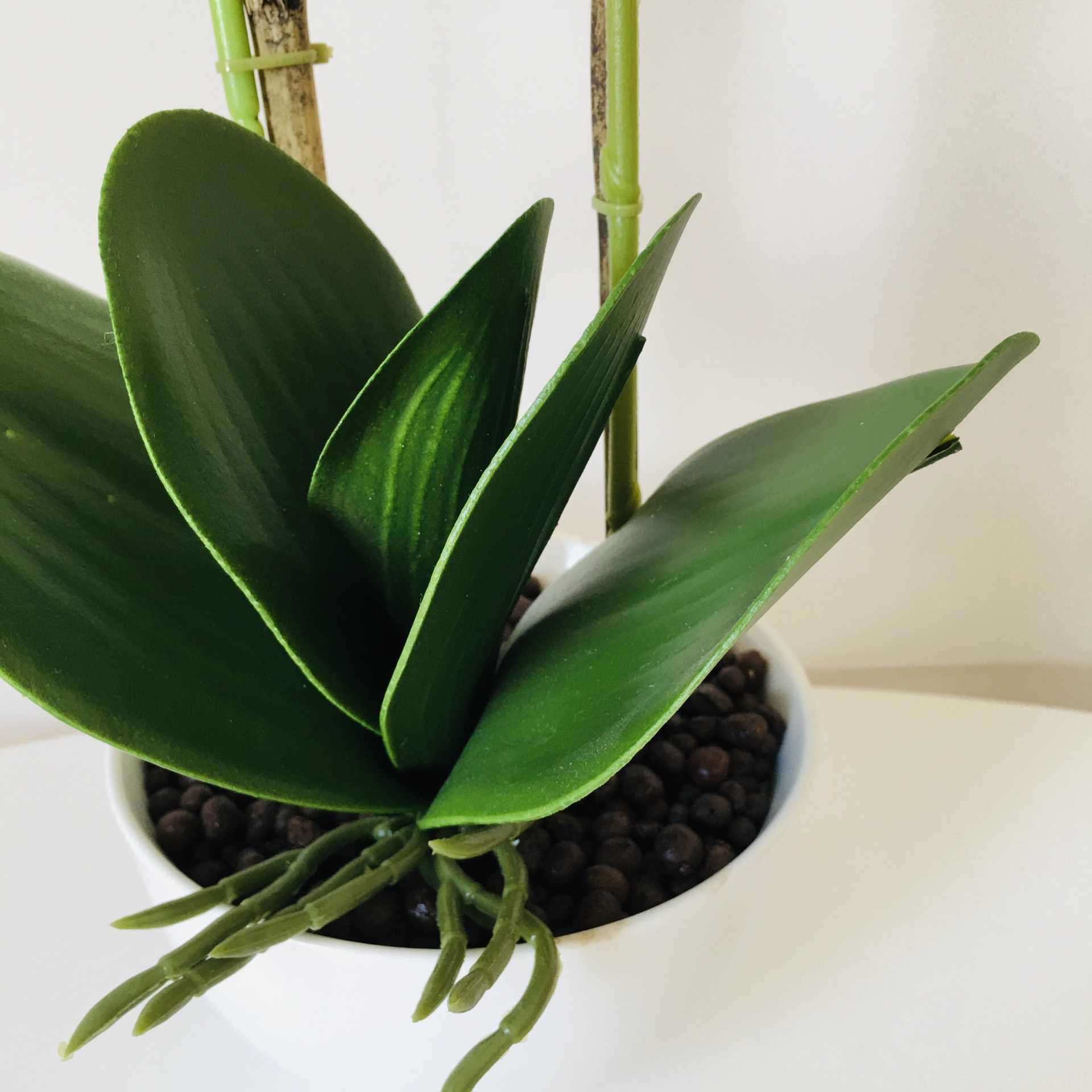 Planta artificial com folhas verdes largas em vaso branco
