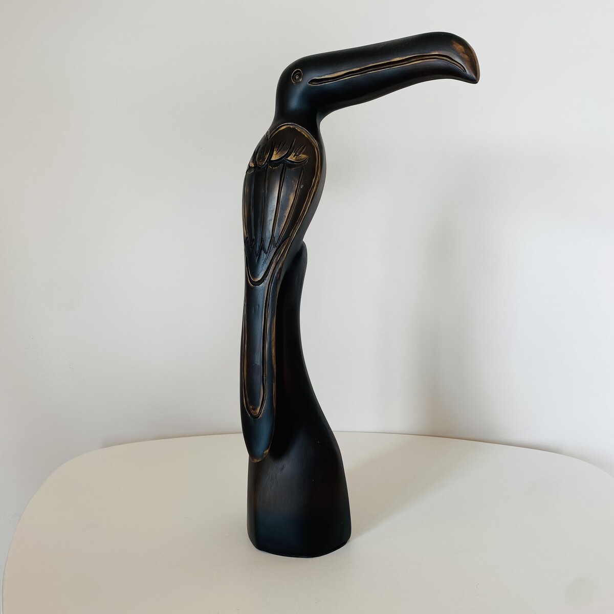 Escultura de pássaro preto em madeira sobre superfície branca