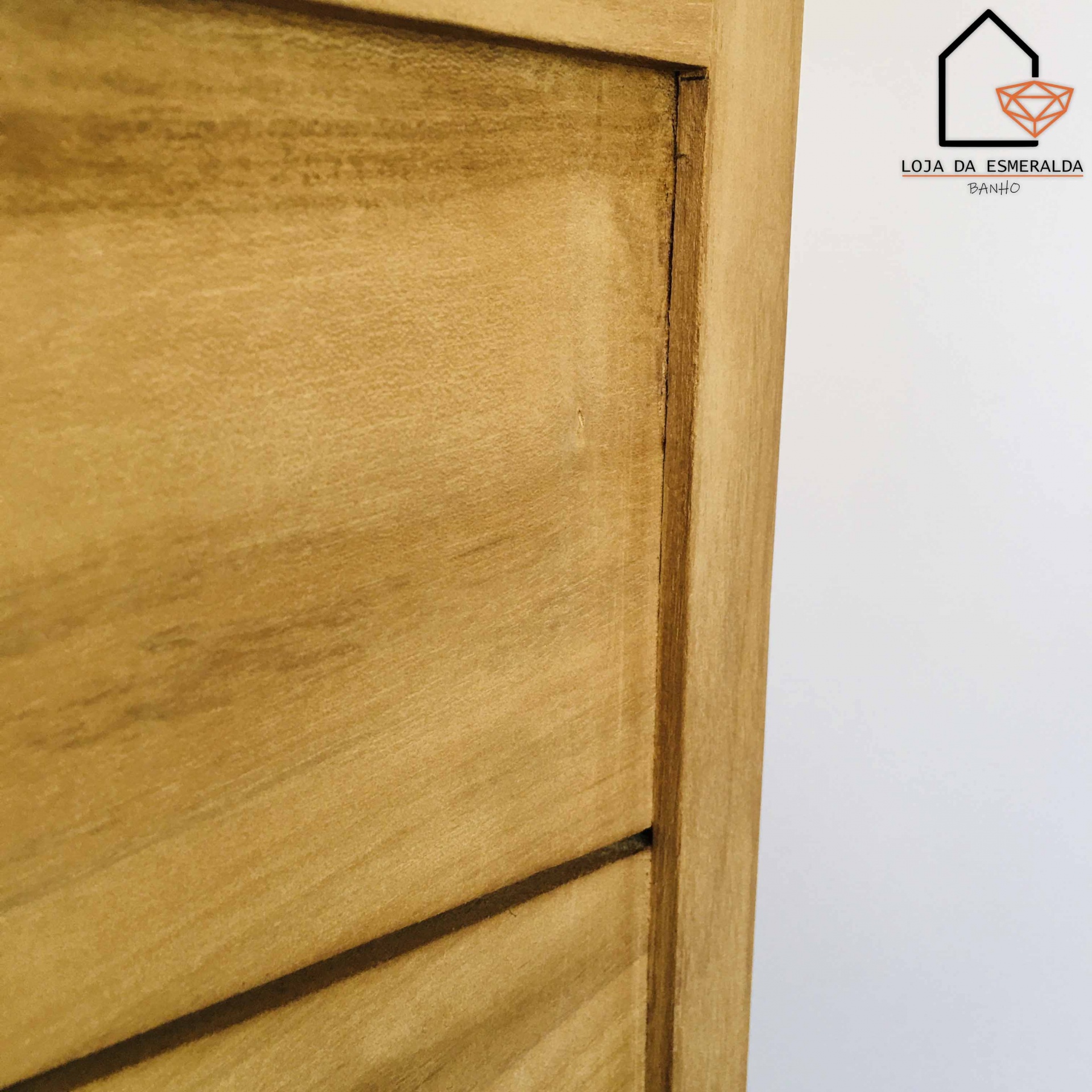 Móvel em madeira clara com logótipo LOJA DA ESMERALDA BAIRRO na parede branca