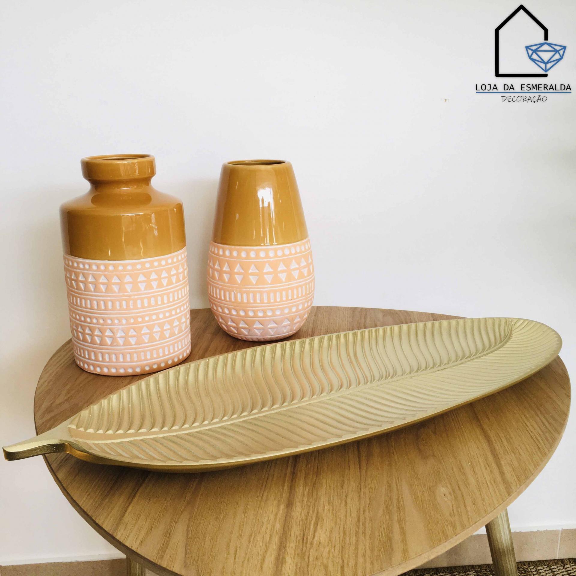 dois vasos cerâmicos decorativos e um prato decorativo em forma de folha sobre uma mesa de madeira