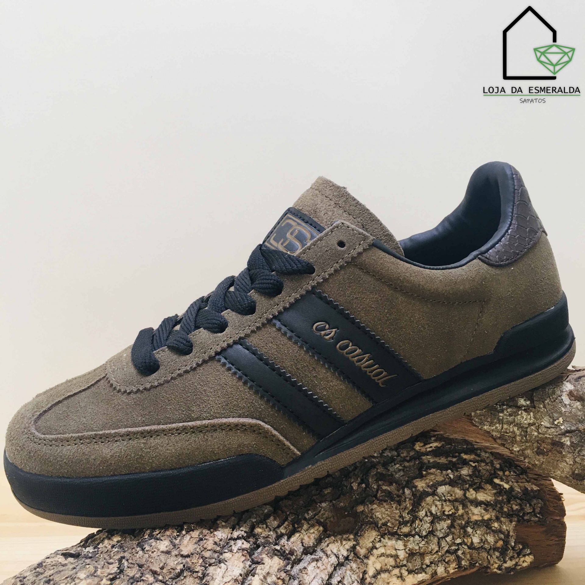 Ténis masculino castanho e preto em camurça sobre tronco de madeira