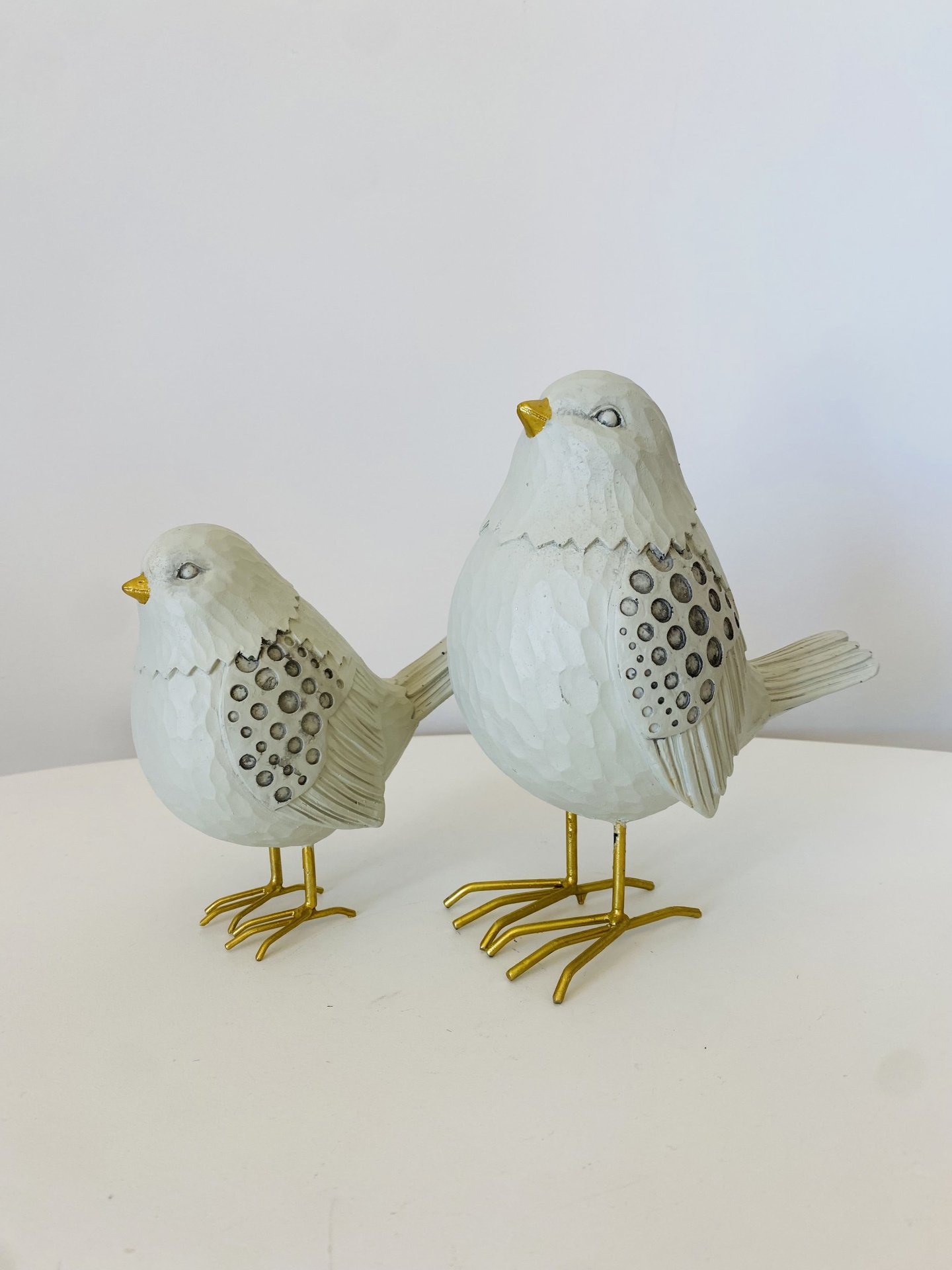 Duas figuras decorativas de pássaros brancos com patas douradas