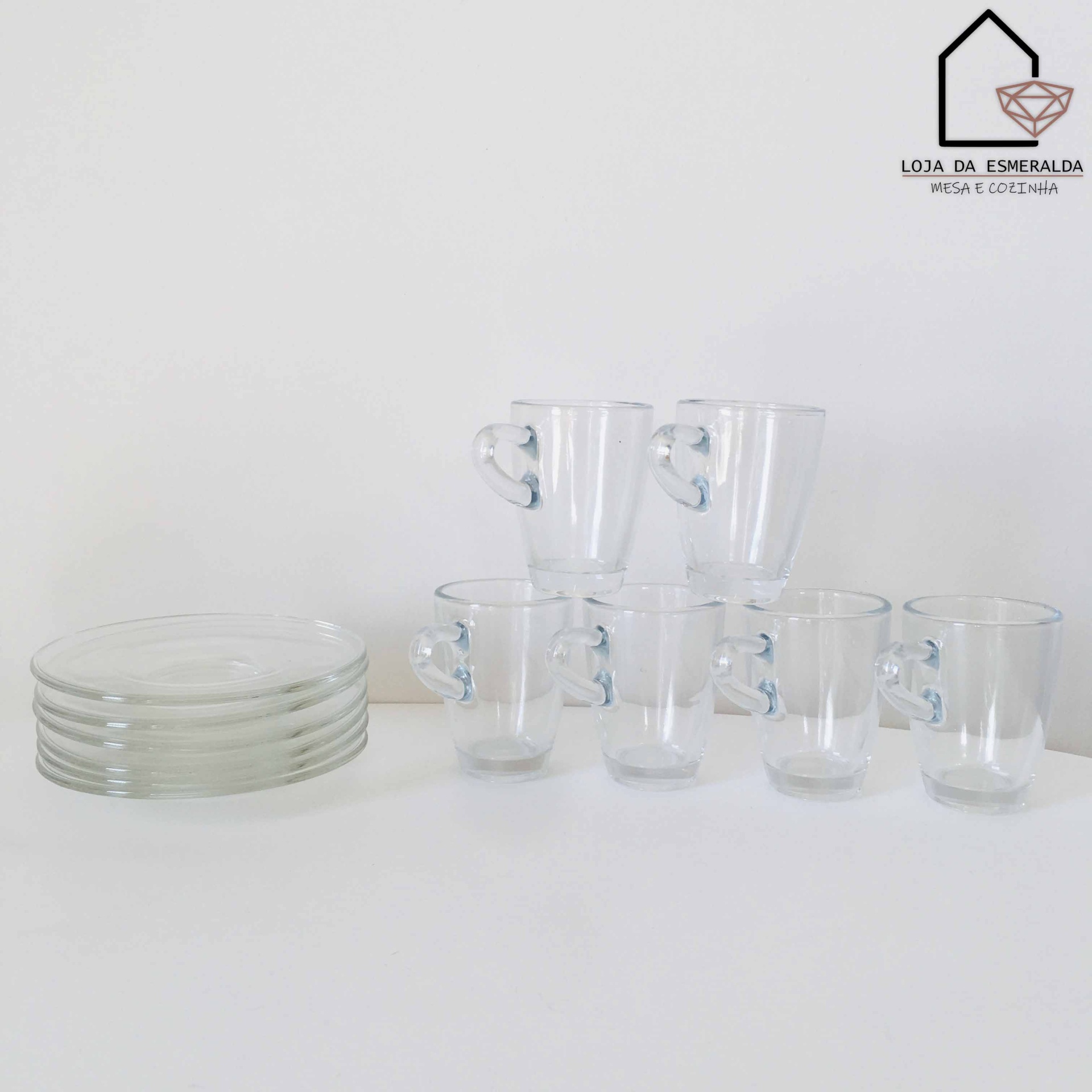 Conjunto de copos de vidro com pega em forma de coração e pratos transparentes sobre mesa branca