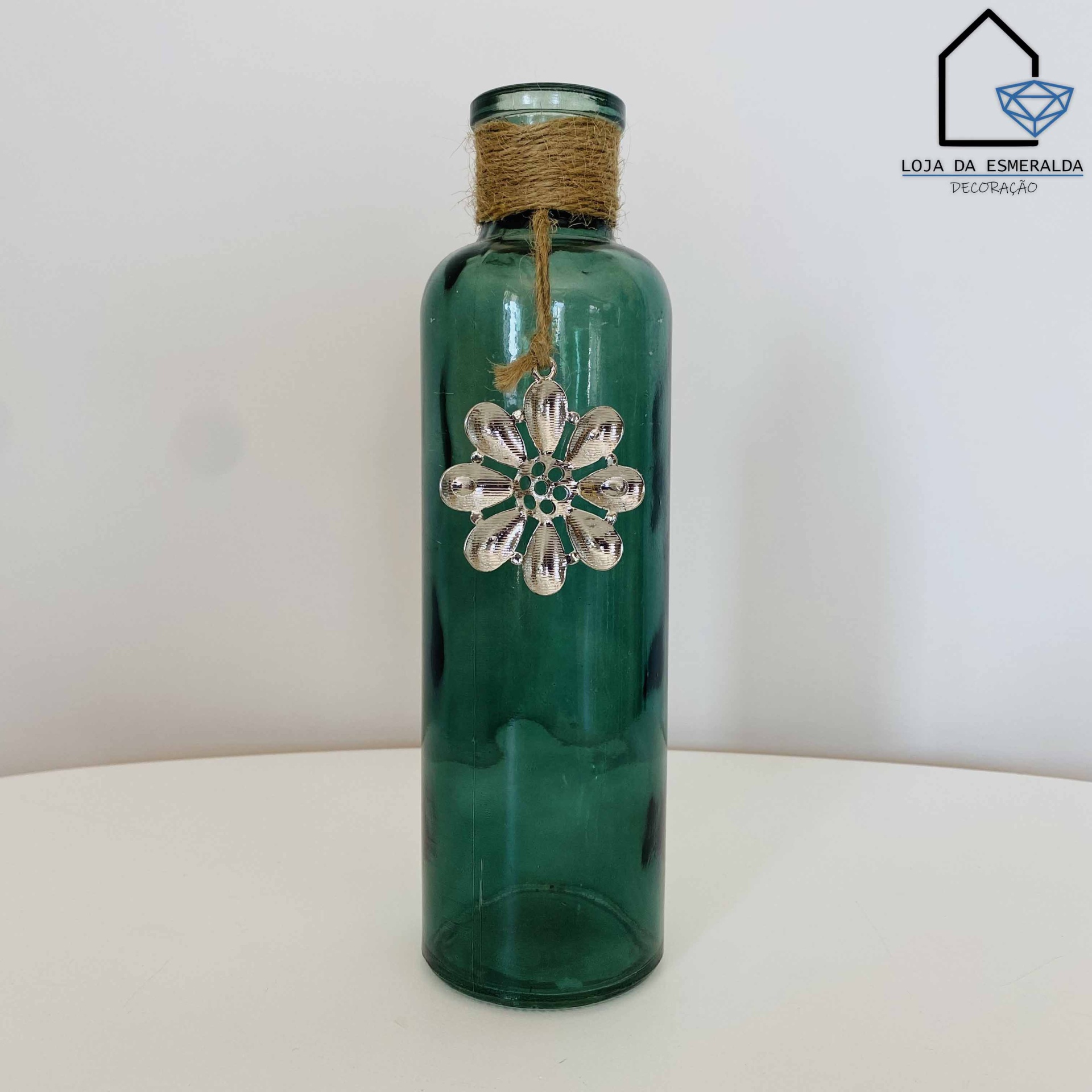 Garrafa decorativa em vidro verde com pendente metálico em forma de flor