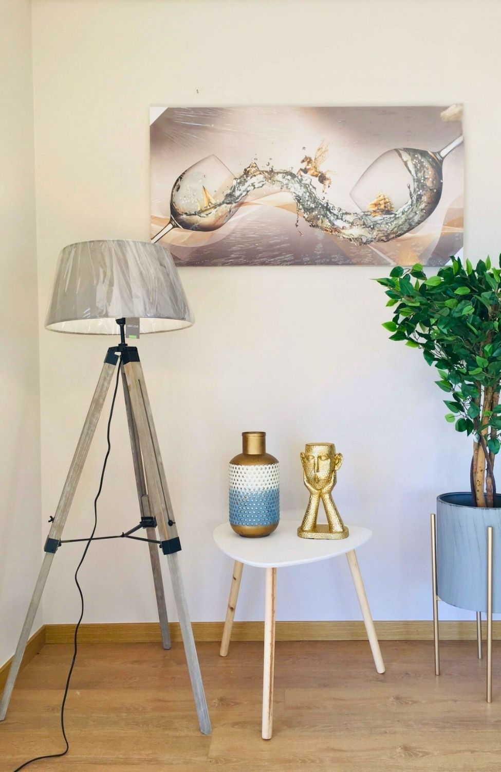 Canto de sala com luminária, mesa com jarro e escultura, vaso com planta