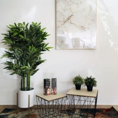 Vaso com planta artificial, mesas com tampo de madeira e estrutura metálica e quadro decorativo com pássaros
