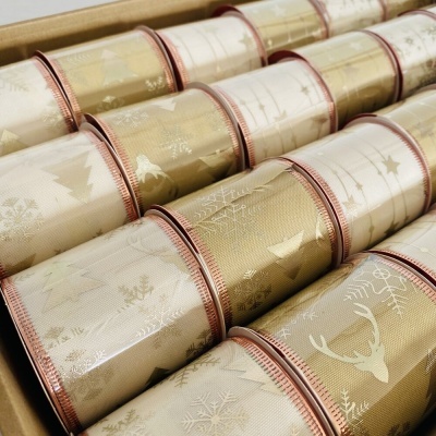 Rolos de fita decorativa de Natal dourada e creme com padrões festivos em caixa