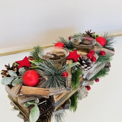 Arranjo decorativo de Natal em madeira com pinhas, folhas, bagas e estrelas vermelhas e velas em copos de vidro