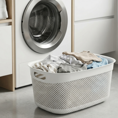 Cesto de roupa suja branco com roupas dentro e máquina de lavar roupa ao fundo