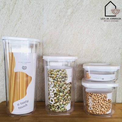 Recipientes transparentes com tampas brancas contendo massa e legumes secos em mesa de madeira