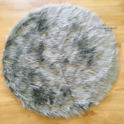 Tapete redondo cinzento de pêlo sintético sobre chão de madeira clara