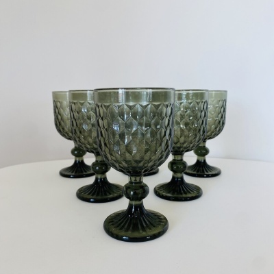 Cinco copos de vidro verde com padrão geométrico texturizado sobre superfície branca