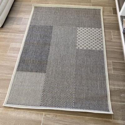 Tapete com padrões geométricos em cinza e bege no chão de pedra castanho claro ao lado de sofá branco