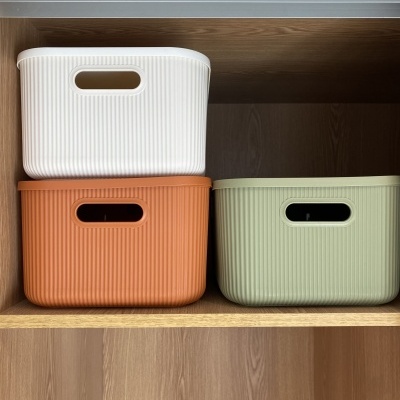 Caixas organizadoras brancas, terracota e verdes numa prateleira de madeira