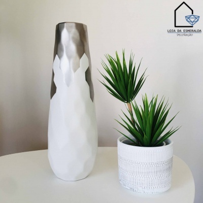 Vaso decorativo alto branco e prateado ao lado de vaso branco com plantas artificiais verdes sobre mesa branca