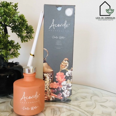 Frasco laranja fosco de difusor de fragrância Acorde com caixa decorada, planta em vaso preto e logotipo no fundo