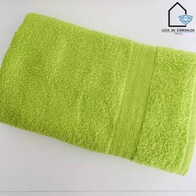 Toalha de banho verde claro com faixa texturada, sobre superfície branca, com logotipo ao lado