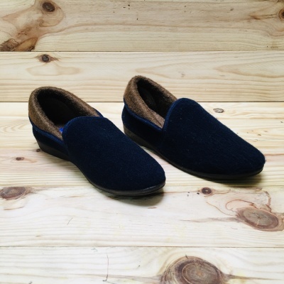 Chinelos ou mocassins azul escuro com interior castanho e solado preto sobre madeira clara