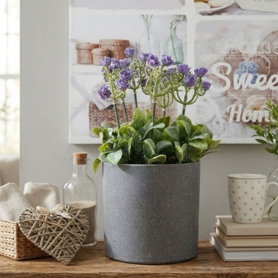 Vaso com planta e flores roxas decorativa sobre mesa de madeira com acessórios