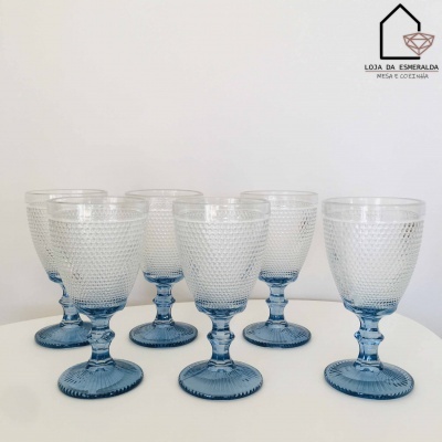 Seis copos de vidro com pé azul e corpo texturizado em fundo branco