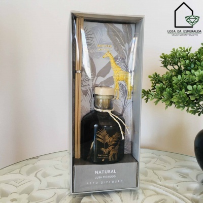 Difusor de varetas Natural com decoração de girafas embalada em caixa transparente sobre mesa branca com planta verde ao lado