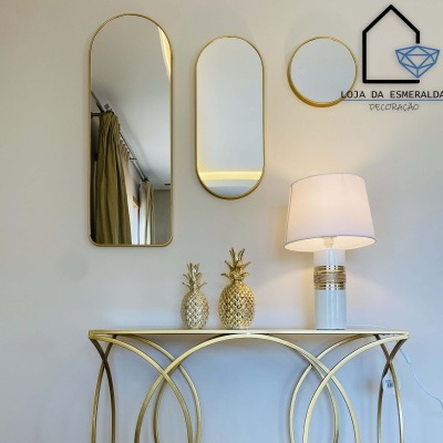 Espelhos decorativos dourados sobre consola dourada com decoração e lâmpada