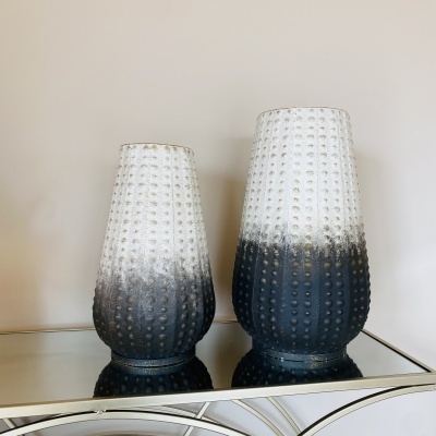 Dois vasos decorativos de vidro em degradé branco para preto sobre superfície espelhada