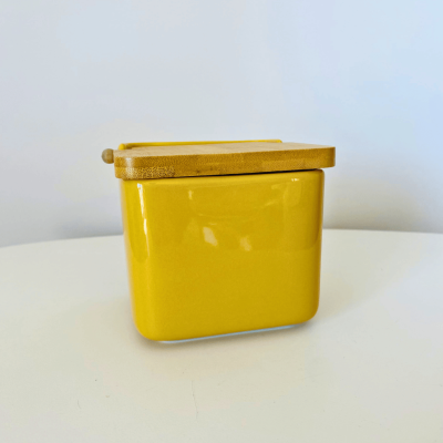 Recipiente amarelo com tampa e colher de madeira
