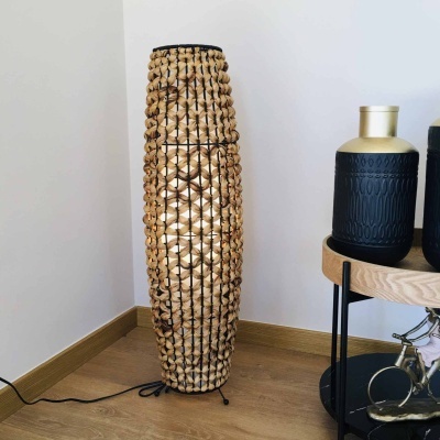 Lâmpada de pé com cordas bege e estrutura preta ao lado de mesa com vasos decorativos