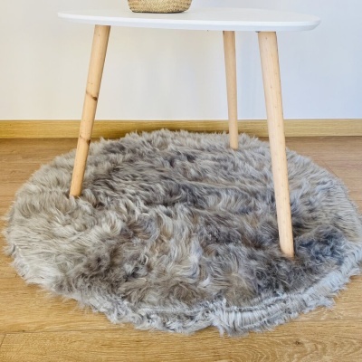 Tapete redondo felpudo cinza sob mesa branca com pés de madeira