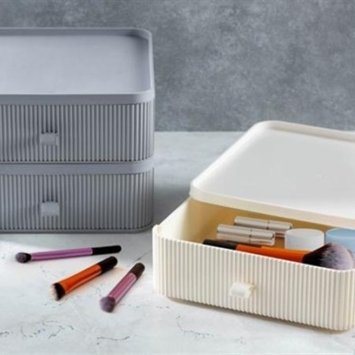 Caixas organizadoras plásticas cinza e creme com pincéis e recipientes de maquilhagem