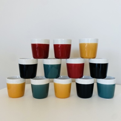 Copos pequenos de cerâmica coloridos com topo branco texturizado, organizados em pirâmide