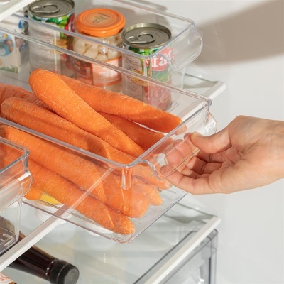 Gaveta transparente no frigorífico com cenouras e latas atrás