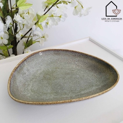 Prato triangular cinza esverdeado com borda castanha e flores brancas ao fundo