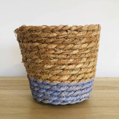 Cesto trançado de palha natural com base azul numa mesa de madeira