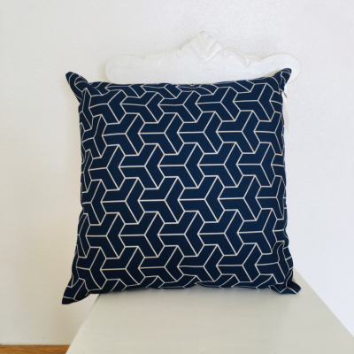 Almofada azul escura com padrão geométrico branco numa cadeira branca