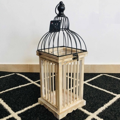 Lanterna decorativa de madeira clara e metal preto com padrão de tapete preto e branco