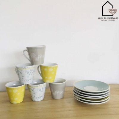 Conjunto de chávenas coloridas e pratos empilhados sobre mesa de madeira