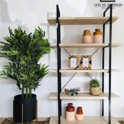 Estante preta e madeira clara com vasos e decoração, planta verde ao lado em suporte metálico dourado