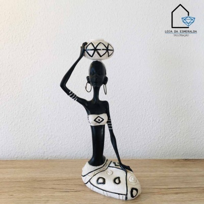 Estátua decorativa de mulher estilizada preto e branco com vaso na cabeça sobre superfície de madeira