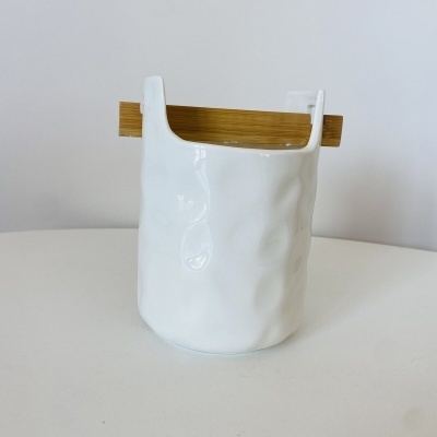 Vaso branco em cerâmica com tábua de madeira numa superfície branca