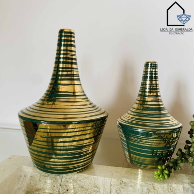 Dois jarros decorativos dourados e verdes com listras sobre superfície de pedra