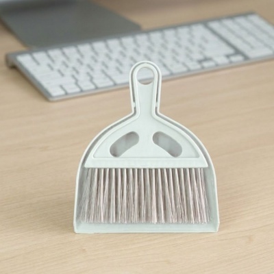 Peneira e escova cinza claro sobre mesa de madeira clara com teclado branco ao fundo