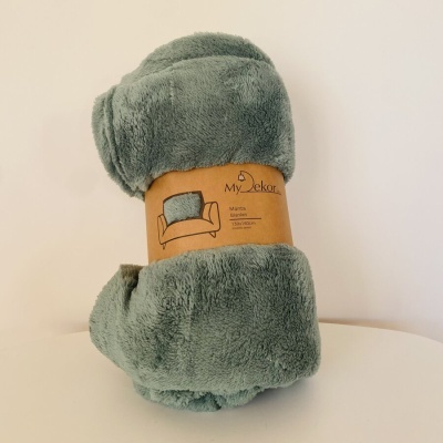 Manta felpuda verde enrolada com etiqueta My Dekor